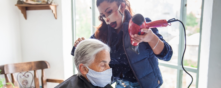 An insured mobile hairdresser cuts elderly woman’s hair