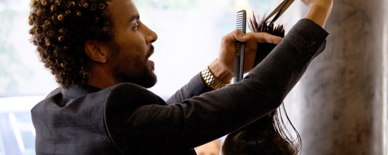 An insured Hairstylist cutting hair with scissors
