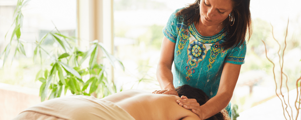 Massage therapist with a South Carolina business insurance massages client’s back


