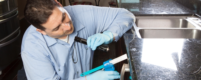 A man using a flashlight to inspect appliance