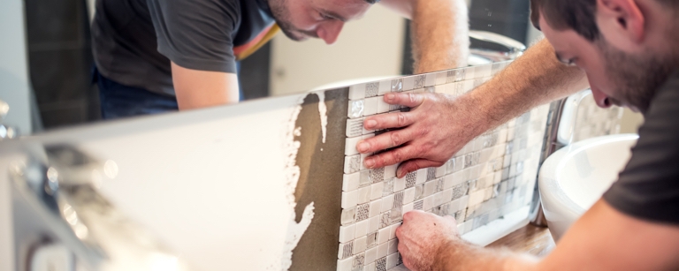 Contractor who has home improvement insurance is installing tiles in a bathroom 

