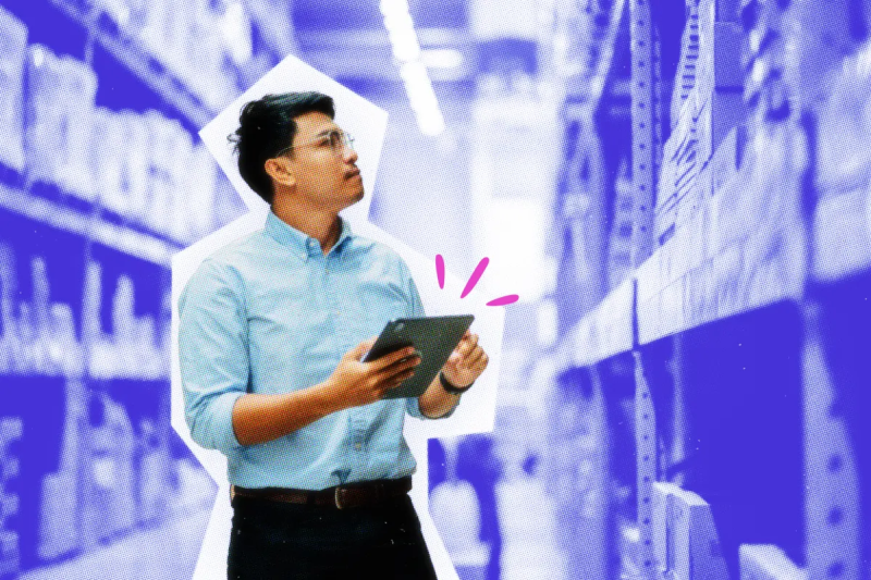 Man in a warehouse aisle using a tablet.