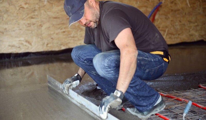 A contractor kneels to do floor installation work.