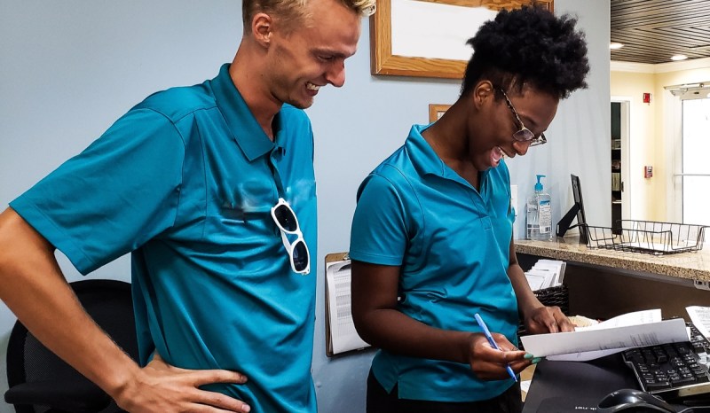 photo of a man and woman wearing blue t-shirts, overlooking paperwork at a desk