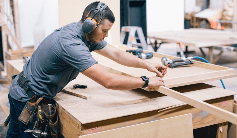 Carpenter at work, wearing ear protection and tool belt.