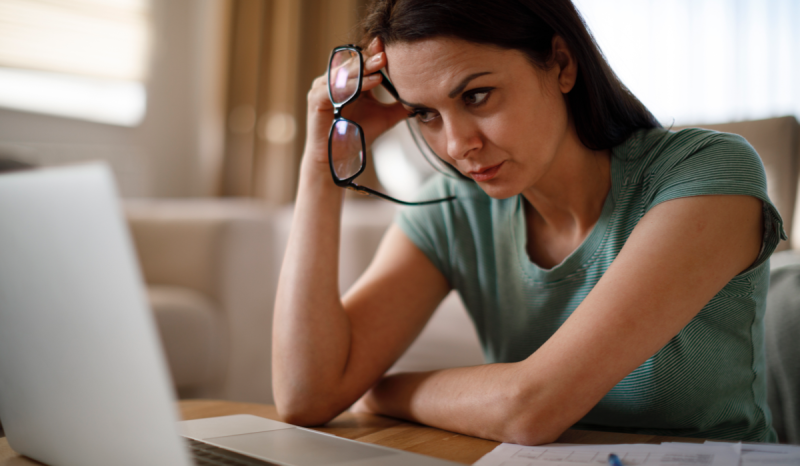 A woman looks at her laptop screen with concern.