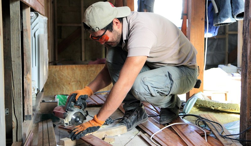 Virginia contractor wearing safety goggles and gloves using a sander