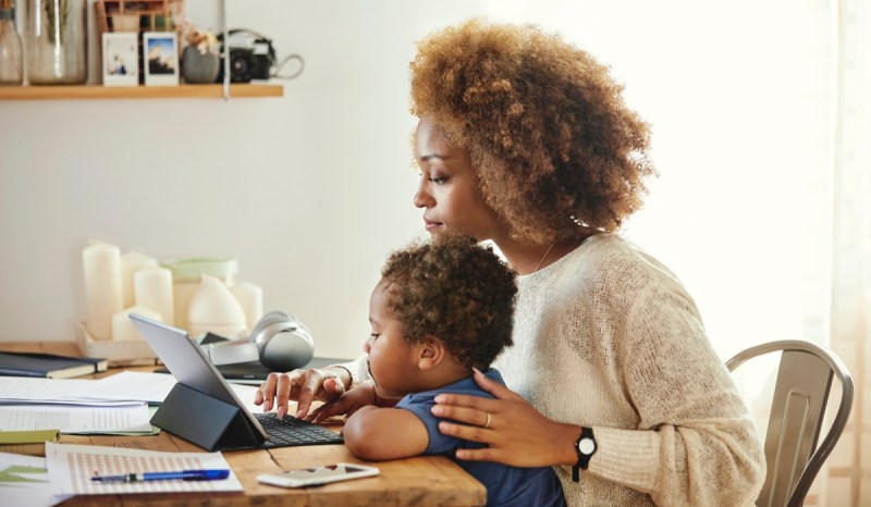 A woman with an Iowa business license works on a tablet with her baby.