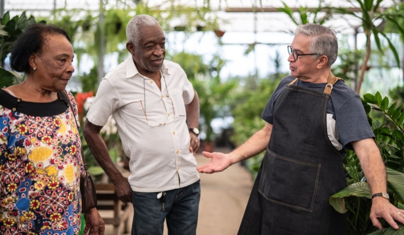 One business owner of a plant nursery talking to two customers as if he knows them very well.