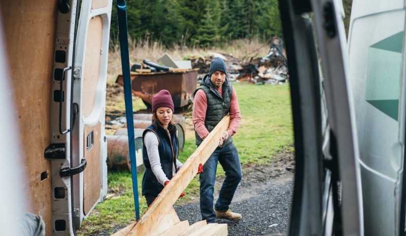 Two contractors with a North Dakota business license load wood into the back of a van.