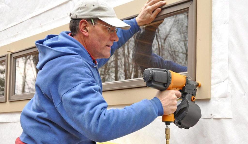A contractor who owns general contractor license in Connecticut is using a drill to install new windows on a building