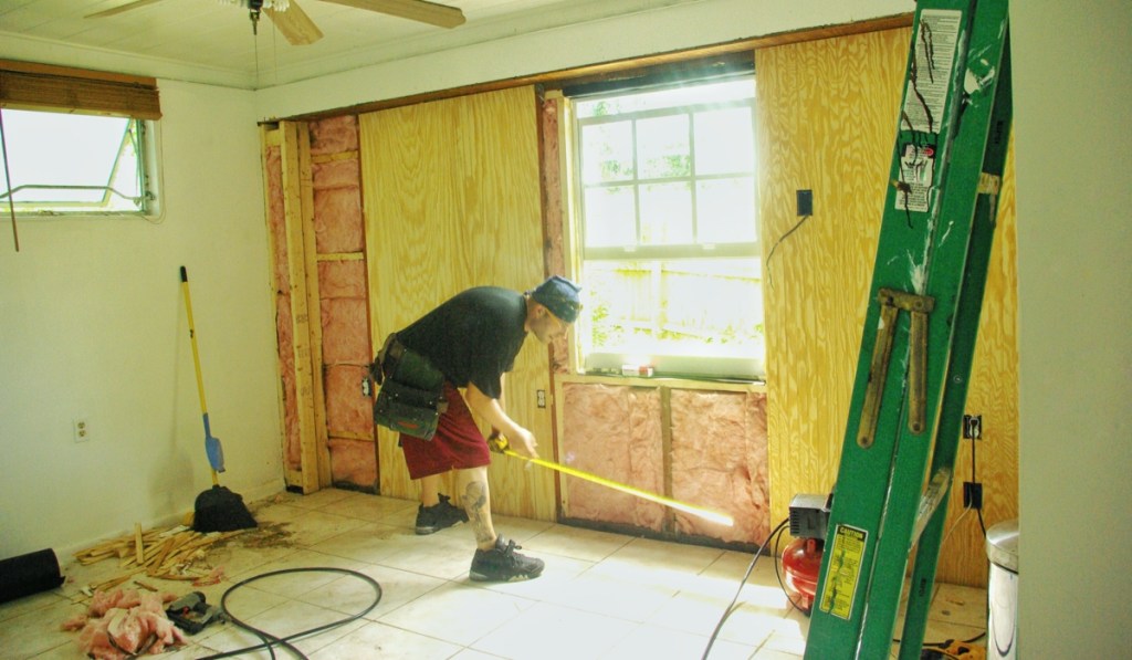 A contractor repairs wall damage from a storm.