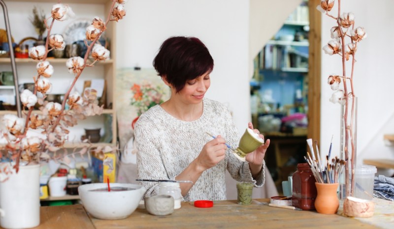 Women in shop painting a ceramic cup.