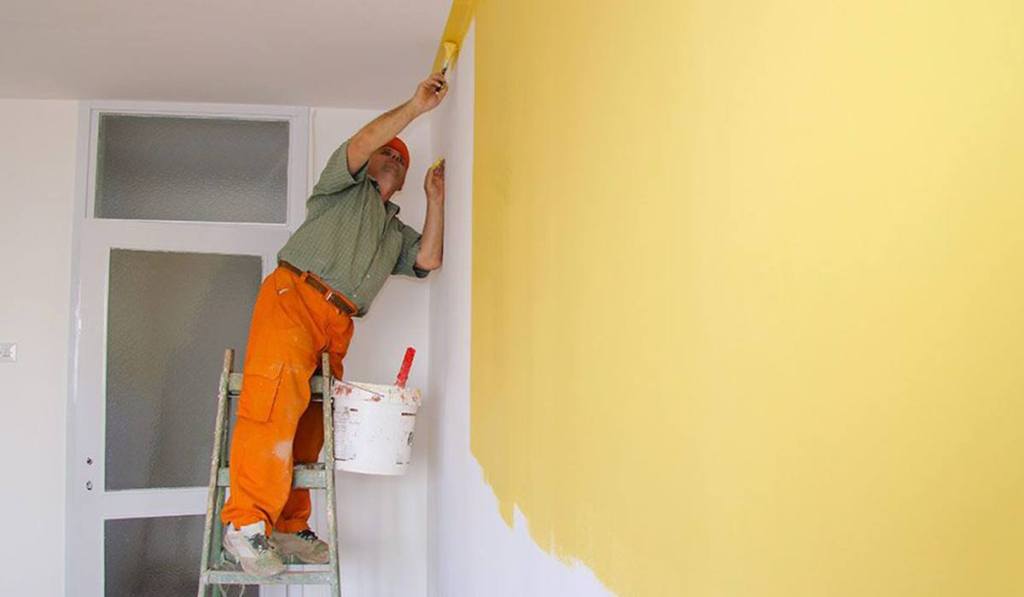 A man is painting a customer's wall after learning how to bid a paint job