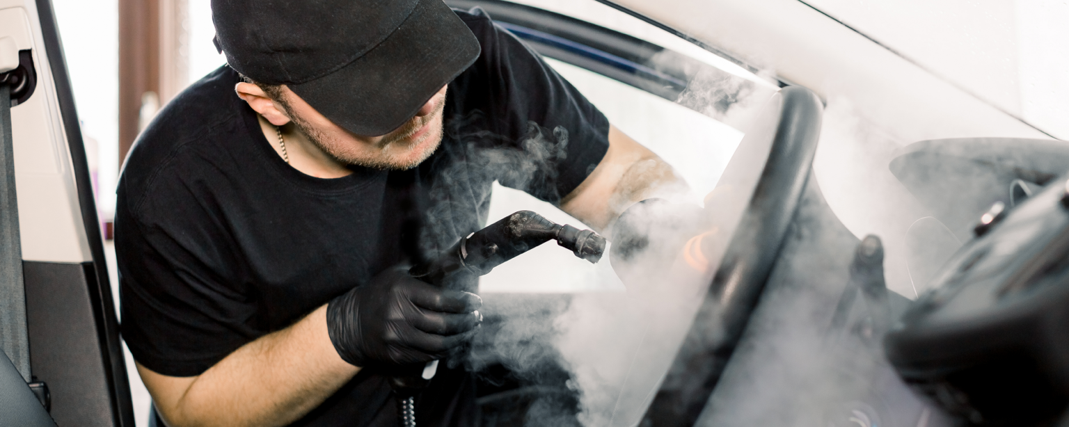 Auto detailer users steamer on steering wheel