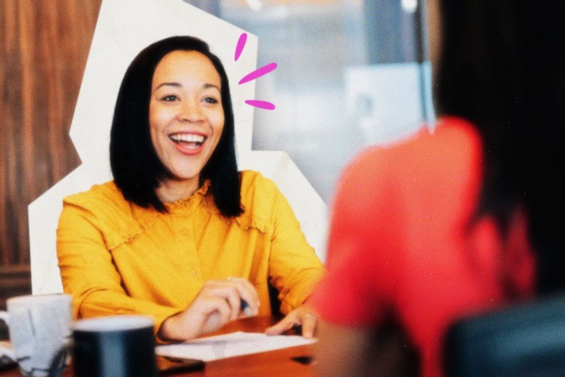 Smiling management consultant at a table with a client.