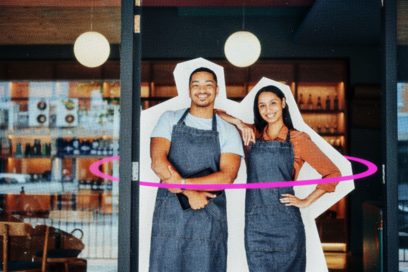 An owner and employee standing in front of their business