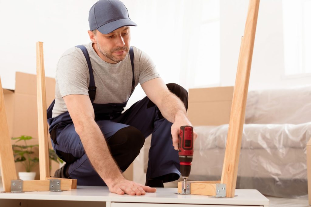 Handyman using drill to attach legs to a table.